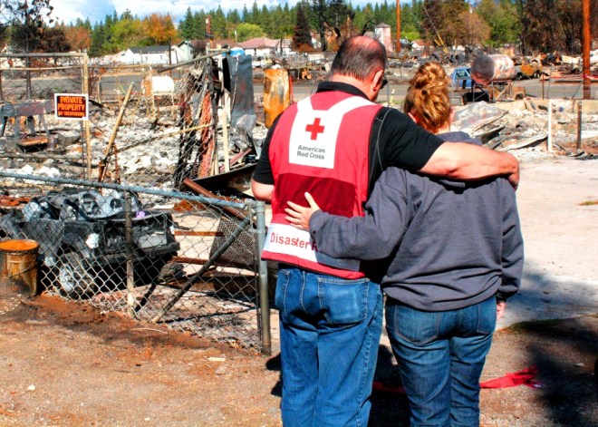 Red Cross volunteer Andy Grossman talks with Weed resident Karly Gregory at the site where her home once stood.