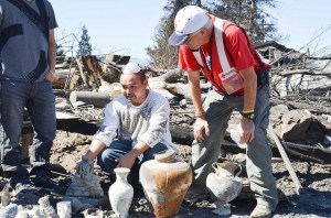 Volunteer Paul Keeton helps members of the Lee family as they go through the remains of their home in Weed.